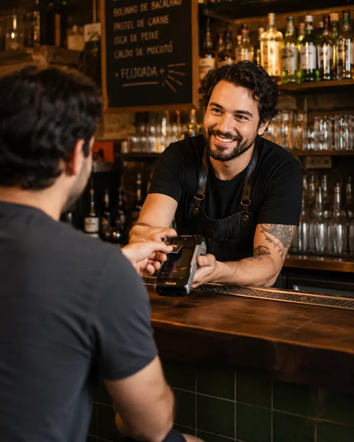 Atendimento no balcão de um bar usando maquininha integrada